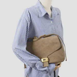 Vue détaillée du sac bandoulière en suède, sac élégant avec boucle métallique.