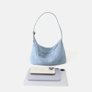 Détail de sac bandoulière hobo en cuir tissé à la main, texture souple et finitions métalliques.