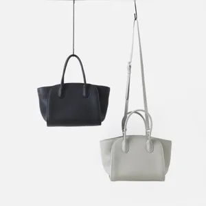 Détail de cabas minimaliste en cuir véritable, côtés structurés, poignées et bandoulière.