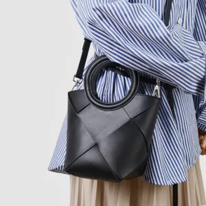 Black leather geometric woven handbag, stylish circular handle shoulder crossbody bag detail.