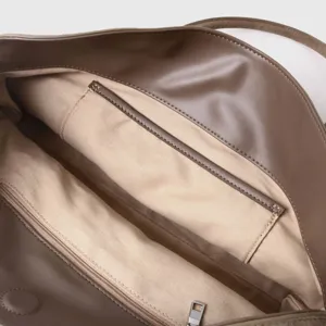 Detail interieur de sac cabas en cuir marron avec doublure en toile et poche zippee.