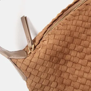 Gros plan des détails d'un sac en cuir tissé marron, montrant le savoir-faire.