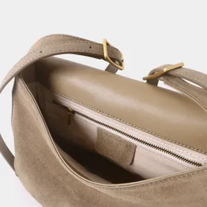 Détail intérieur du sac bandoulière en suède avec poche zippée et sangle réglable.