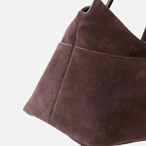 Gros plan sur la texture du sac à main en daim marron foncé, montrant des finitions soignées.