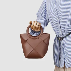 Detailed view of a chic brown woven handbag featuring a round handle and modern geometric design.
