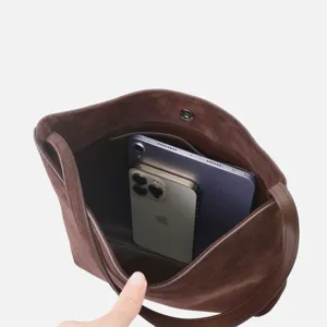 Détail intérieur de sac seau en daim marron montrant une grande capacité de rangement.