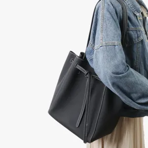Sac seau noir en cuir véritable avec coutures contrastantes et bandoulière élégante chic.