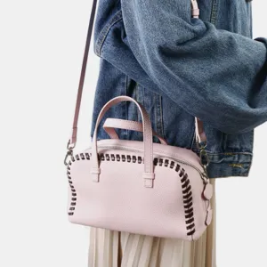 Détail de sac Boston en cuir rose avec bordure tressée contrastée, design élégant.