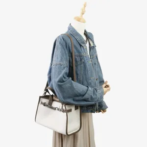 Détail cabas en toile et cuir, sac bandoulière marron et blanc avec fermoir métallique.