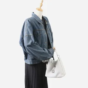 Détail de sac seau en cuir blanc avec texture grainée et fermeture à anneau métallique.