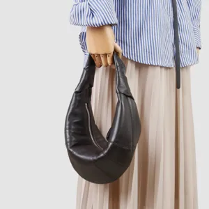 Vista detallada del bolso hobo de piel negra tipo cruasan con silueta curvada.