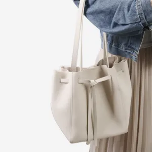 Vue détaillée du sac seau en cuir minimaliste avec cordon de serrage élégant et nœud papillon chic.
