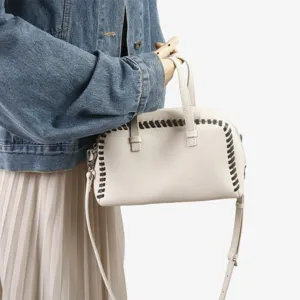 Vue détaillée d'un sac à main Boston en cuir blanc avec coutures contrastées et bandoulière.
