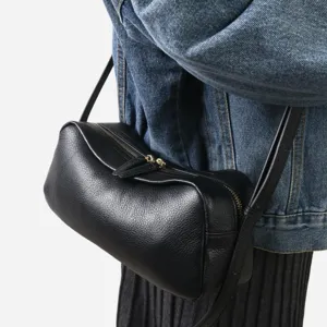 Détail du sac bandoulière cylindrique en cuir souple noir, mettant en valeur les ferrures.