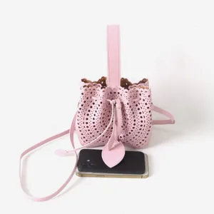 Vue détaillée du sac seau en cuir rose ajouré avec poignée et motifs délicats.