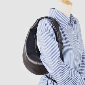 Detalle de bolso croissant de cuero marrón oscuro, elegante bolso hobo con diseño segmentado.