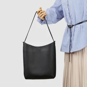 Dettaglio in primo piano della borsa a spalla minimalista in pelle nera con texture.