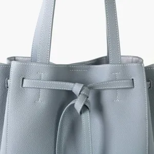 Gros plan détaillé du sac cabas en cuir gris avec élégante ceinture à nœud avant et belles coutures.