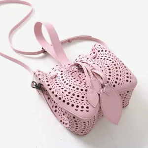 Détail de sac seau en cuir perforé rose, élégant sac à main ajouré bandoulière.