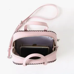 Sac a main Boston en cuir rose avec bordure tressee contrastee, poignees et bandouliere.