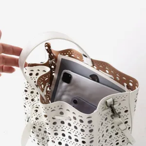 Grand sac seau en cuir blanc avec motif de decoupe au laser et doublure interieure marron.