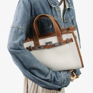 Détail de sac cabas en toile et cuir avec coutures soignées, fermoir tournant et double poignée.