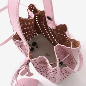 Sac seau ajouré en cuir rose, vue détaillée présentant un délicat motif floral perforé.