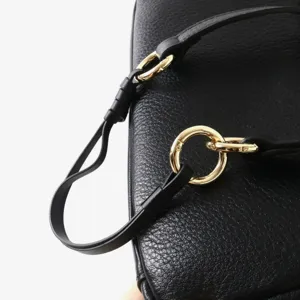 Vue de detail du sac a main en cuir noir texture avec des anneaux metalliques dores.