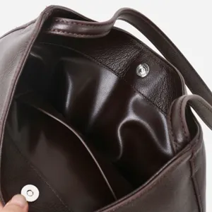 Primo piano dello scomparto interno e della chiusura magnetica di una borsa secchiello in vera pelle.