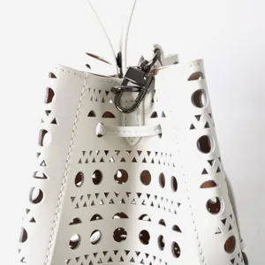 Vue détaillée du sac seau en cuir blanc avec motifs de découpe laser géométriques.
