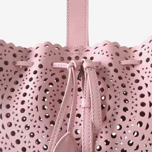 Vue détaillée du sac seau en cuir rose perforé présentant des motifs géométriques.