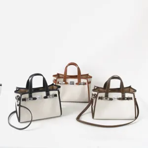 Sac cabas élégant en toile avec garniture en cuir véritable, bandoulière et fermoir en métal.