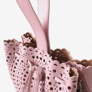 Magnifique petit sac seau ajouré en cuir rose tendance avec détail de bordure festonnée.