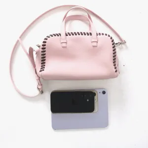 Sac a main Boston en cuir rose avec details de coutures contrastees, anses et bandouliere.