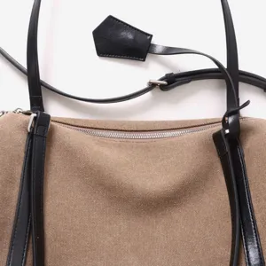 Vue détaillée de la fermeture éclair et des finitions en cuir du sac en toile.