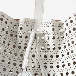 Vue détaillée du sac seau en cuir blanc doté de motifs ajourés géométriques élégants.