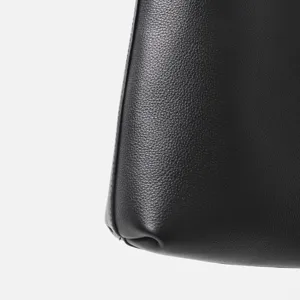 Dettaglio in primo piano della borsa in vera pelle nera con cuciture curate e trama.