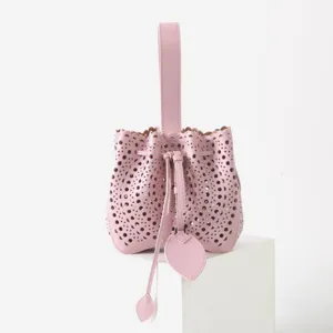 Élégant sac seau en cuir rose avec motif ajouré laser et cordon de serrage pratique.