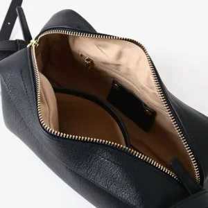 Vue détaillée du sac en cuir noir avec fermeture éclair et doublure intérieure beige