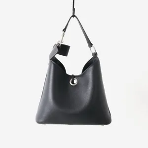 Gros plan sur la texture en cuir noir foulonné et le détail de la fermeture anneau en métal.