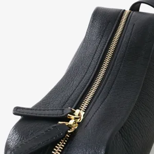 Gros plan détail du sac en cuir véritable noir avec fermeture éclair dorée et texture grainée.
