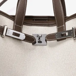 Vue de détail du sac cabas en toile et cuir avec serrure tournante et coutures.