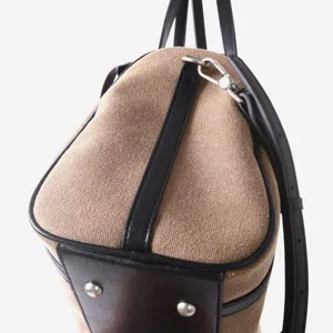 Gros plan sur les détails d'un sac en toile et cuir avec coutures et quincaillerie.