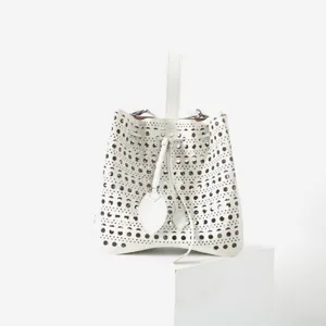 Vue détaillée du sac seau perforé en cuir blanc, motif découpé au laser, design élégant.