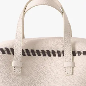 Détail de sac à main en cuir de luxe avec poignées contrastées beige élégant.