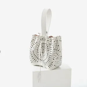 Vue détaillée du sac seau en cuir blanc ajouré avec poignée supérieure et cordon serrage.