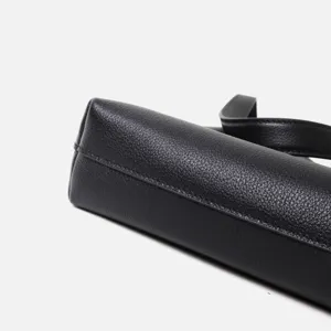 Primo piano dettagliato di una borsa a spalla in vera pelle nera con cuciture e trama.