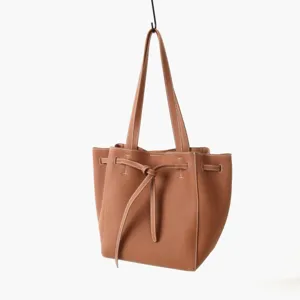 Détail du sac cabas en cuir marron avec nœud élégant et coutures contrastées.