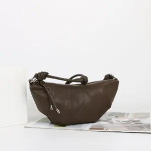Sac bandoulière croissant en cuir marron avec lanière nouée et fermeture éclair.