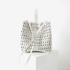 Gros plan sur le sac seau en cuir blanc doté d'un motif géométrique découpé au laser.